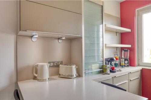 cocina con encimera blanca y paredes rojas en Chambre tropicale 3, en Courcouronnes
