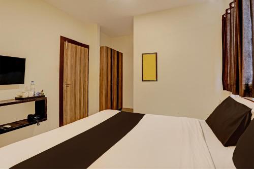 a bedroom with a white bed and a television at Capital O Saharsh Grand Near Shilparamam in Hyderabad