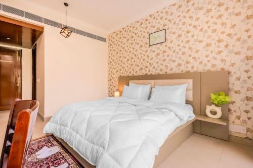 sypialnia z dużym łóżkiem z białymi prześcieradłami w obiekcie Fresh Air Green Flair 1 BHK with Balcony w mieście Gurgaon