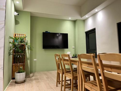 a dining room with a table and chairs and a flat screen tv at Komorebi homestay in Chiayi City