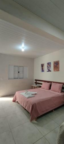 a bedroom with a large bed with pink sheets at Pousada Jamaica in Igarassú