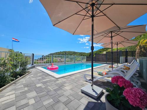 une piscine avec un parasol et deux chaises dans l'établissement Apartment Tomic 2, à Makarska