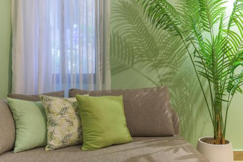 a couch with pillows in a living room with a plant at Jade Guesthouse In The Old Souks in Batroûn