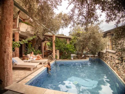 a woman sitting in a pool with a child in the water at Apartments and Rooms Levantin Inn in Sveti Stefan