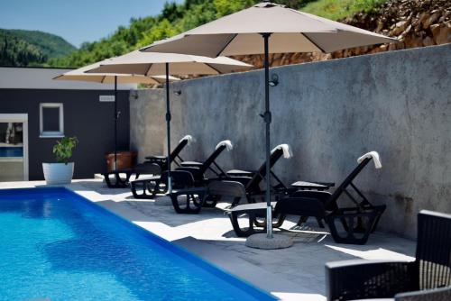 a group of chairs and umbrellas next to a pool at Villa Pietra in Stolac