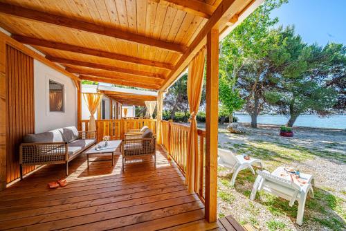 a wooden deck with a couch and chairs on it at Mobile Homes Camp Perna - Adriatic Kampovi in Orebić