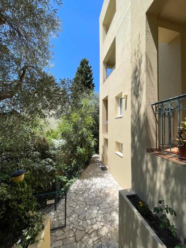 a walkway between two buildings with trees on the side at Apartmani Agape in Petrovac na Moru