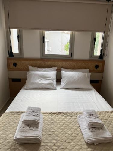 a bedroom with a bed with two towels on it at Thines Comfort Living in Néa Péramos