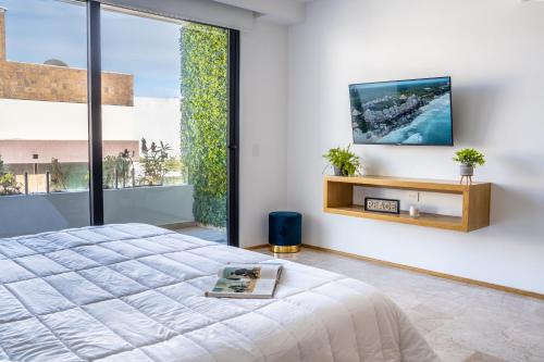 a bedroom with a bed and a tv on a wall at Luxury Condo en Menesse CocoBeach in Playa del Carmen