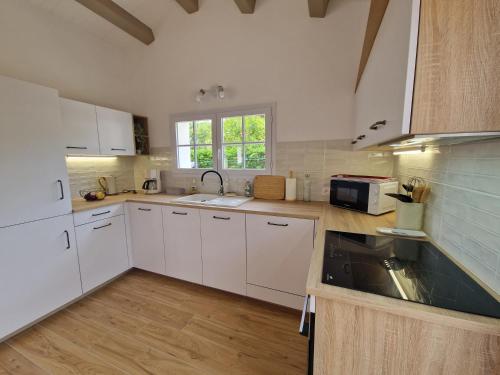 une cuisine avec des armoires blanches et un évier dans l'établissement Maison familiale à Barbâtre face à la dune, 3 chb, 2 SDB, 8 personnes, à Barbâtre
