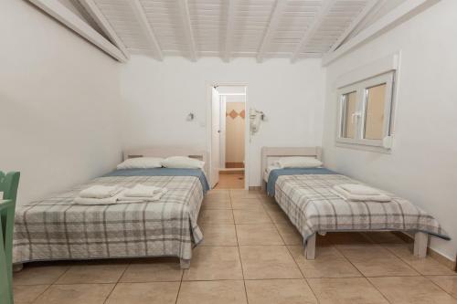 two beds in a room with white walls and tile floors at olivensun bungalow 3 in Gythio