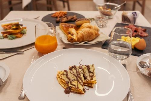 a table topped with plates of food and orange juice at Hotel Rosa in Baveno