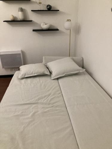 un lit avec deux oreillers dessus dans une chambre dans l'établissement Studio meublé Gambetta, à Paris