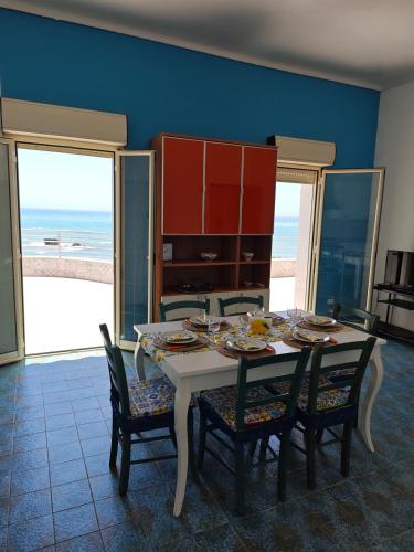 a dining room with a table and chairs and the ocean at La terrazza di Adele in Scoglitti