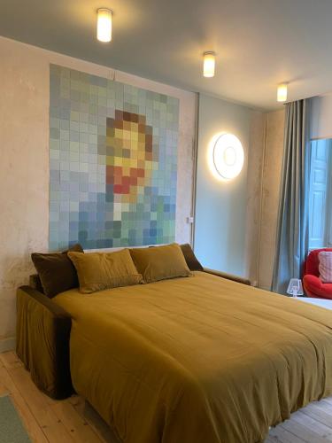 une chambre avec un grand lit avec un tableau au mur dans l'établissement Le studio Grande Maison Perrier, à Montbrison