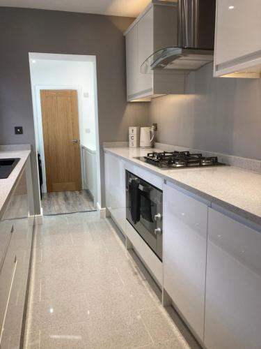 a kitchen with white cabinets and a stove top oven at Cheshire Home Stays in Church Coppenhall