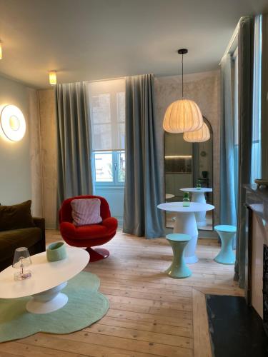 - un salon avec deux tables et un fauteuil rouge dans l'établissement Le studio Grande Maison Perrier, à Montbrison