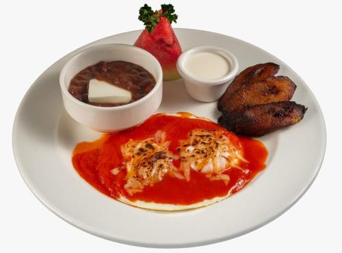 a plate of food with a plate of food with meat and sauce at Hotel Playa Paraíso in Monterrico