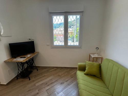 a living room with a green couch and a desk at Casa Marisa in Camporosso