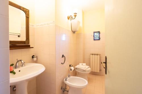 a bathroom with a sink and a toilet and a mirror at Borgo Villa Certano - Case Vacanza in Toscana in Siena