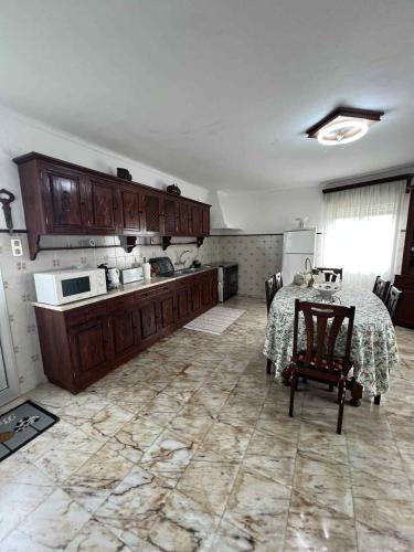 a large kitchen with a table and a refrigerator at Casa da Atalaia in Angra do Heroísmo