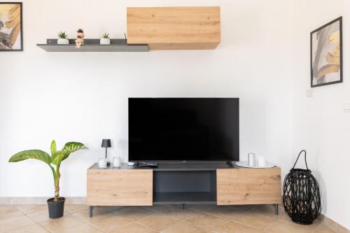 a living room with a flat screen tv on a wooden entertainment center at Long Green House in Sorso