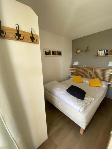 - une petite chambre avec un lit et des oreillers jaunes dans l'établissement Appartement LES PETITS PRINCES, à Agay