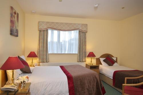 a hotel room with two beds and a window at Murphys of Killarney in Killarney
