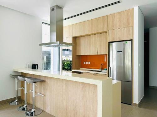 eine Küche mit einer Theke mit Hockern und einem Kühlschrank in der Unterkunft Villa 95 3PN Sanctuary Ho Tram Resort in Hồ Tràm