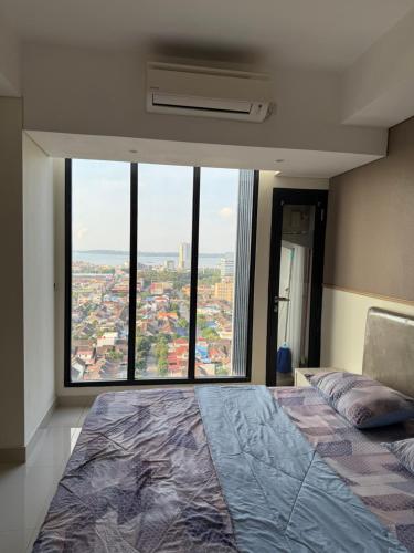 a bedroom with a large bed with a large window at Apartment studio Pollux Habibie in Batam Center