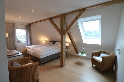 a bedroom with a bed and two chairs and a window at Landhotel Adler in Sigmarszell
