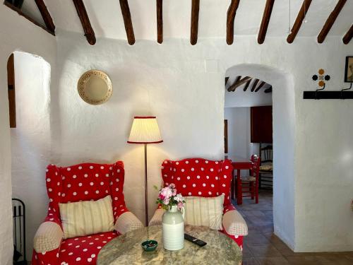 a living room with red chairs and a table at Las casillas de la Villa ALEGRÍAS in Montefrío