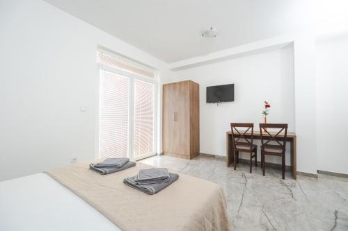 two beds in a room with a table and a television at Apartmani Agape in Petrovac na Moru