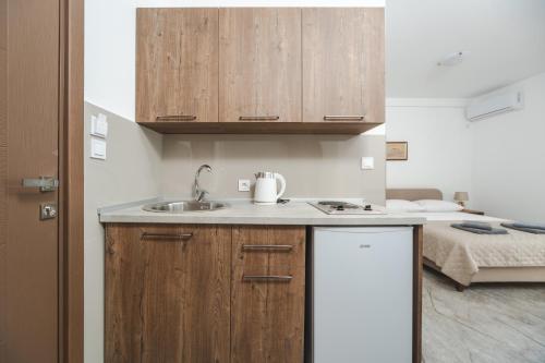 a kitchen with a sink and wooden cabinets at Apartmani Agape in Petrovac na Moru