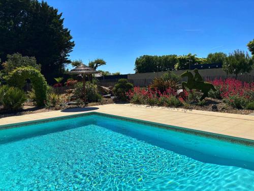 a blue swimming pool in a yard with flowers at Cottage avec piscine au cœur du Saumur Champigny in Souzay-Champigny