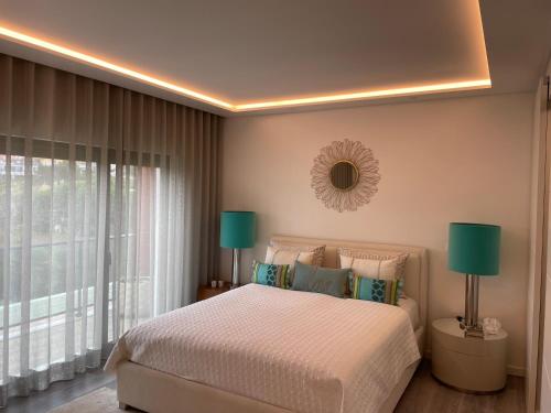 Un dormitorio con una cama con dos lámparas y una ventana. en Sunshine Ericeira, en Ericeira