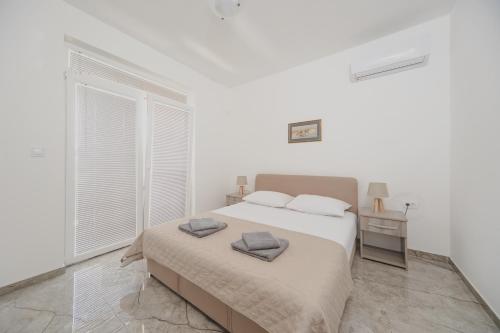 a white bedroom with a bed and a window at Apartmani Agape in Petrovac na Moru