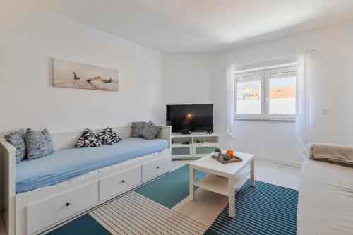 a white living room with a couch and a tv at Costa 27 Beach Apartment - By Y Concept in Costa da Caparica
