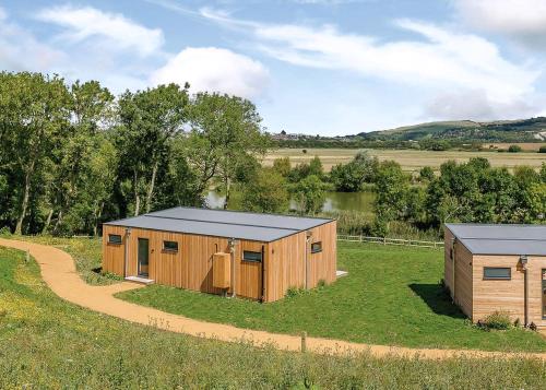 two wooden buildings in a field with a road at Swanborough Lakes Luxury Lodges in Lewes