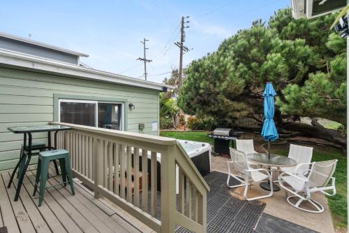 a deck with a table and chairs and an umbrella at O-Side Beach Bungalow with Jaccuzi Blocks to beach in Oceanside