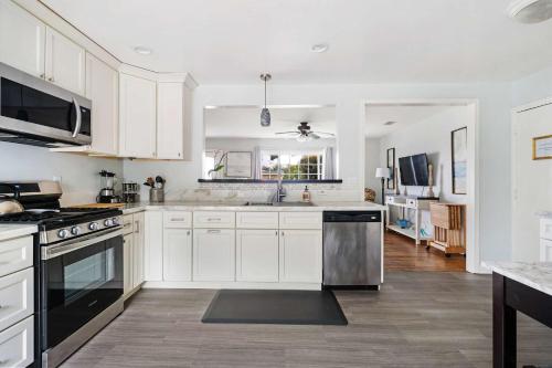 a kitchen with white cabinets and stainless steel appliances at O-Side Beach Bungalow with Jaccuzi Blocks to beach in Oceanside
