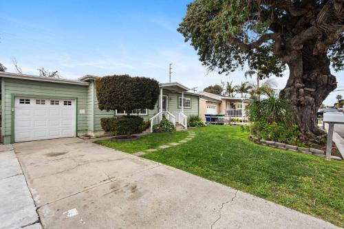 a green house with a garage and a tree at O-Side Beach Bungalow with Jaccuzi Blocks to beach in Oceanside