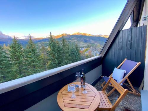a table and chairs on a balcony with a view at Le Duplex - Cosy & Vue Montagnes in Barcelonnette
