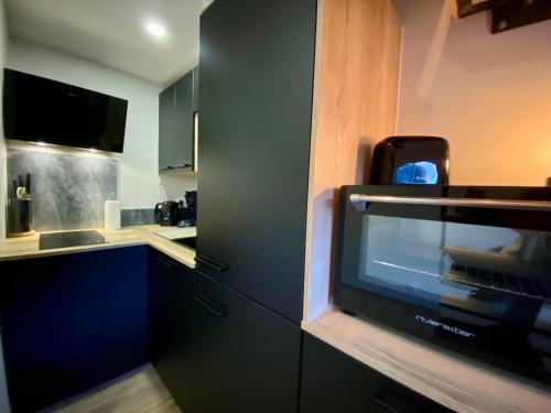 a small kitchen with a tv in a cabinet at Le Duplex - Cosy & Vue Montagnes in Barcelonnette