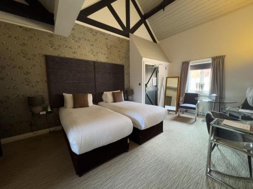 a hotel room with two beds and a desk at The Mount Country Manor Hotel & Golf Wolverhampton in Wolverhampton