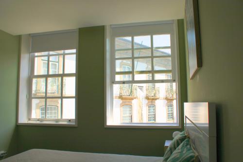 two windows in a room with a building at Alfred Studio in Guimarães