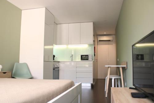 a bedroom with a bed and a kitchen with white cabinets at Alfred Studio in Guimarães