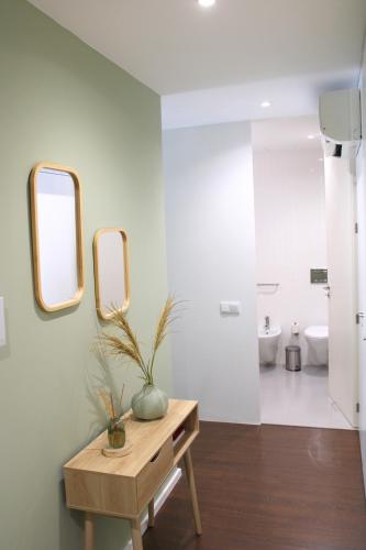 a bathroom with two mirrors and a wooden table at Alfred Studio in Guimarães