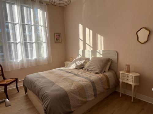 Un dormitorio con una cama y dos ventanas. en La casuccia Galliéni, en Rochefort