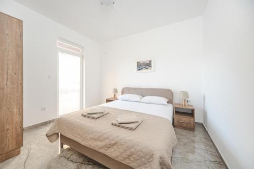 a white bedroom with a bed with two towels on it at Apartmani Agape in Petrovac na Moru